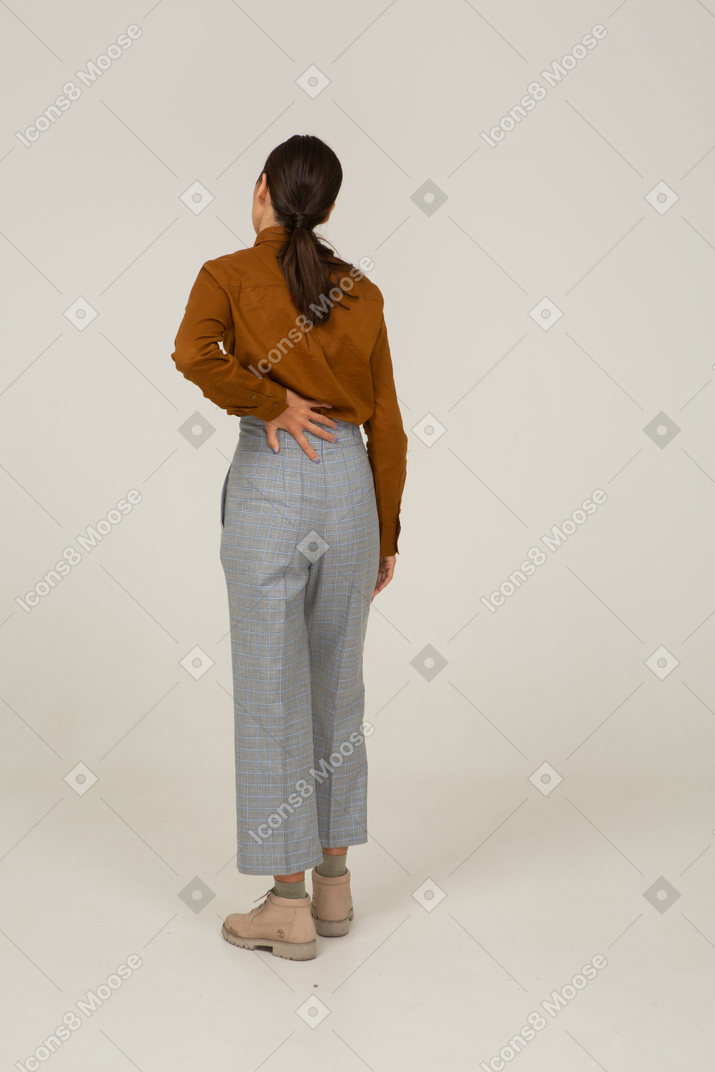 Vista posterior de una joven mujer asiática en calzones y blusa tocando la espalda