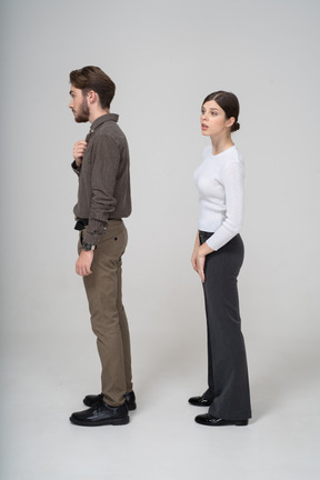 Vista lateral de um jovem casal curioso com roupas de escritório