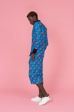 Black man in blue pajamas standing on the pink background