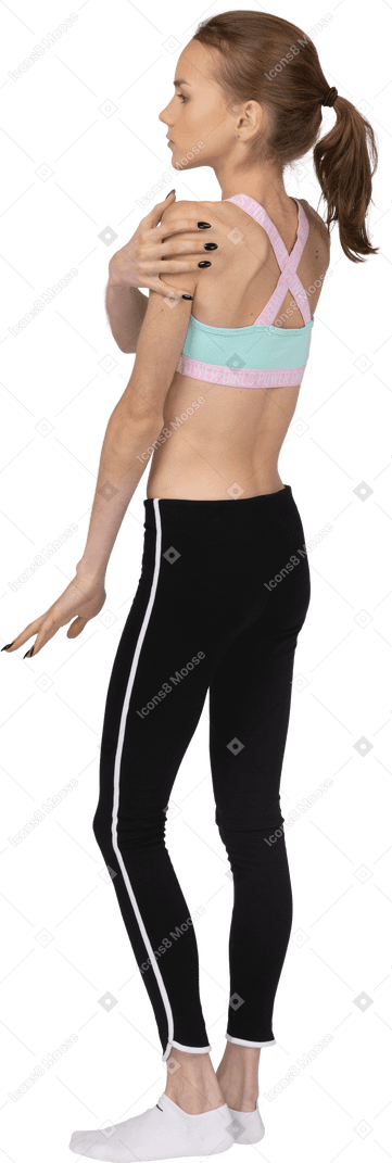 Vista traseira a três quartos de uma adolescente em roupas esportivas tocando seu ombro