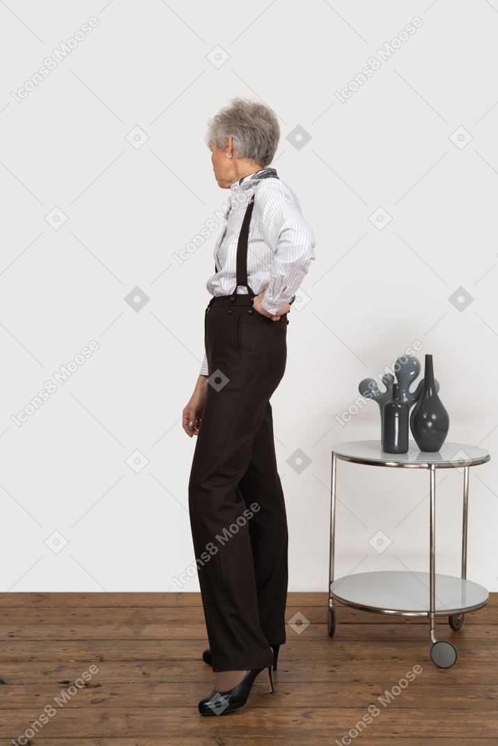 Vista lateral de una anciana curiosa en ropa de oficina mirando a un lado