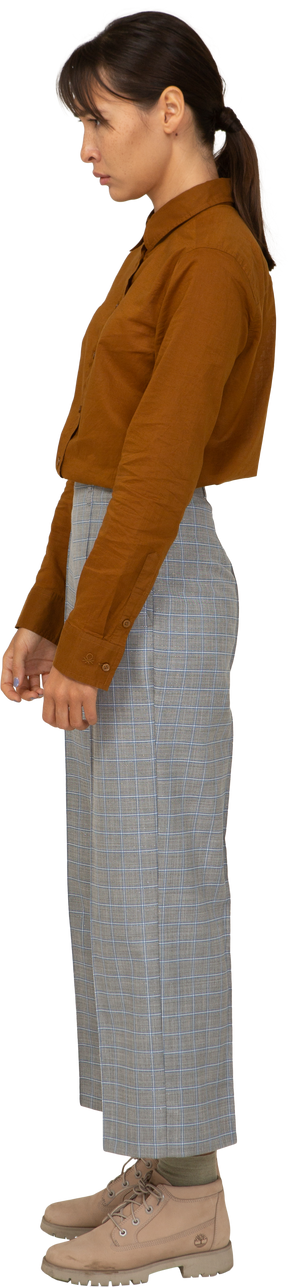 Vista laterale di una giovane donna asiatica sconvolta in calzoni e camicetta