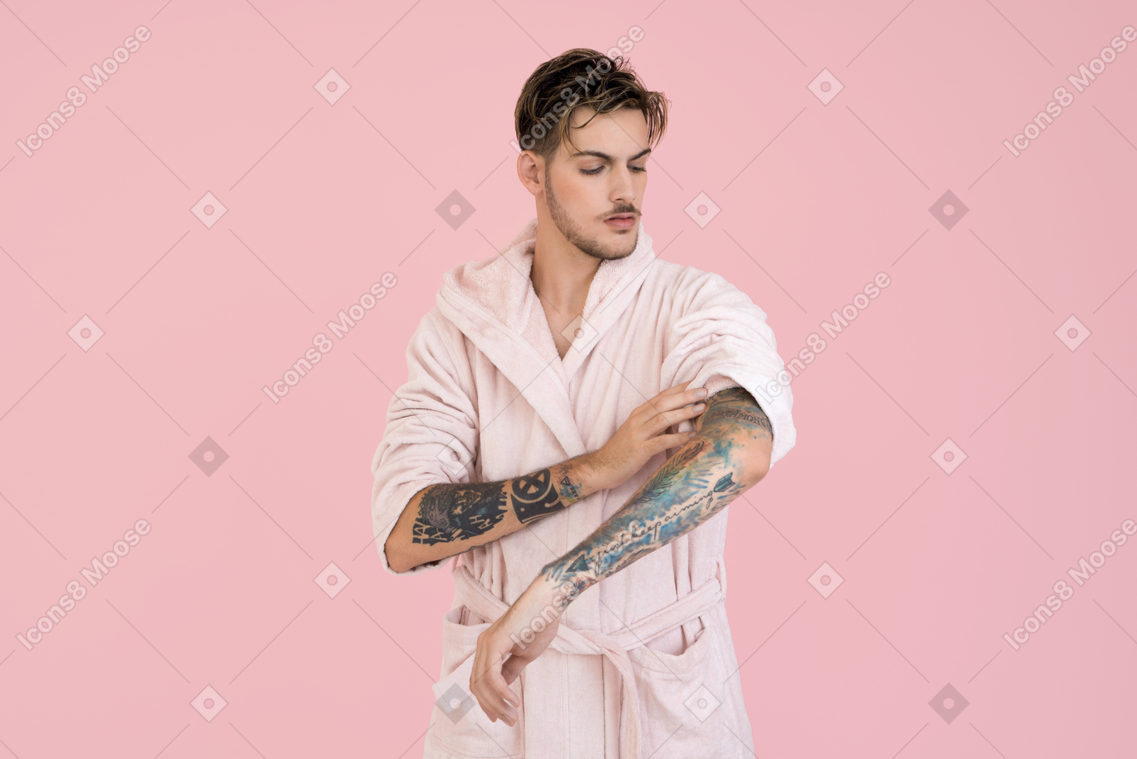 Handsome young in pink robe looking at his hand