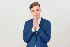Un joven apuesto con traje y las manos cruzadas parece mendigar