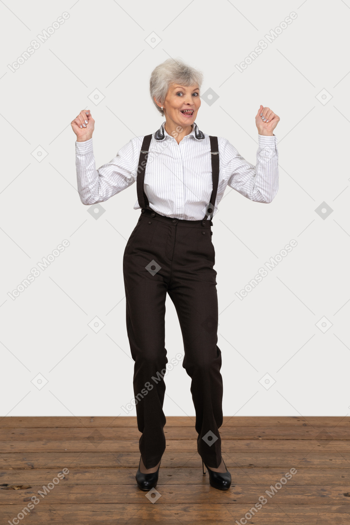 Vista frontal de uma senhora feliz com roupa de escritório, levantando as mãos