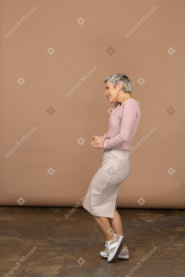 Vue latérale d'une femme heureuse dans des vêtements décontractés posant sur une jambe