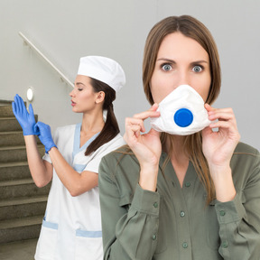 Shocked woman with face mask standing in front of a nurse