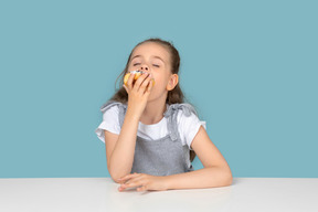 Jolie petite fille dégustant un beignet