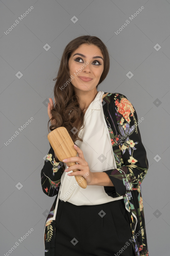 Cute smiling young woman brushing her long hair