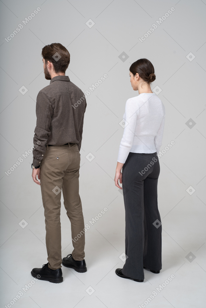 Vista traseira de três quartos de um jovem casal irreconhecível com roupas de escritório, parado