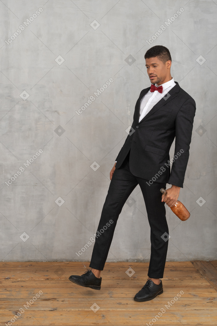 Tipsy young man walking with a bottle in his hand