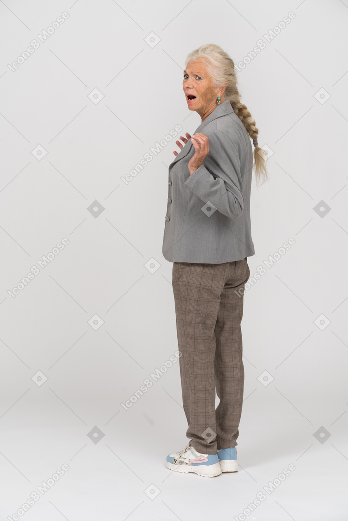 Vista trasera de una anciana sorprendida en traje gesticulando