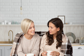Deux femmes assises dans la cuisine avec des tasses de thé