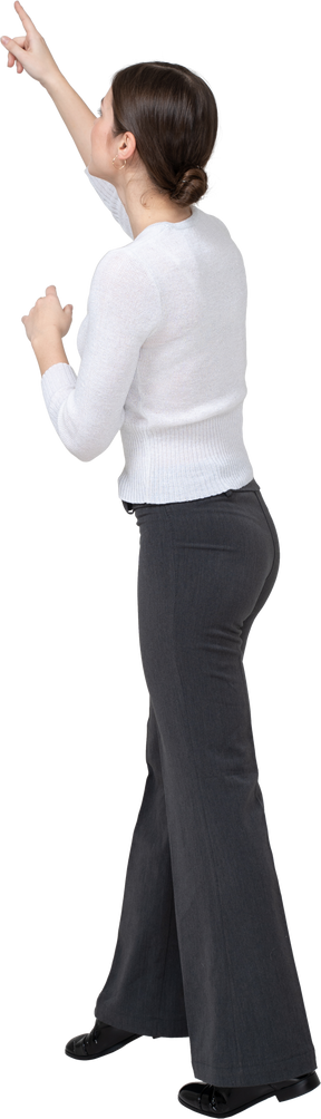 Vista lateral de uma mulher com roupas casuais apontando para cima com um dedo