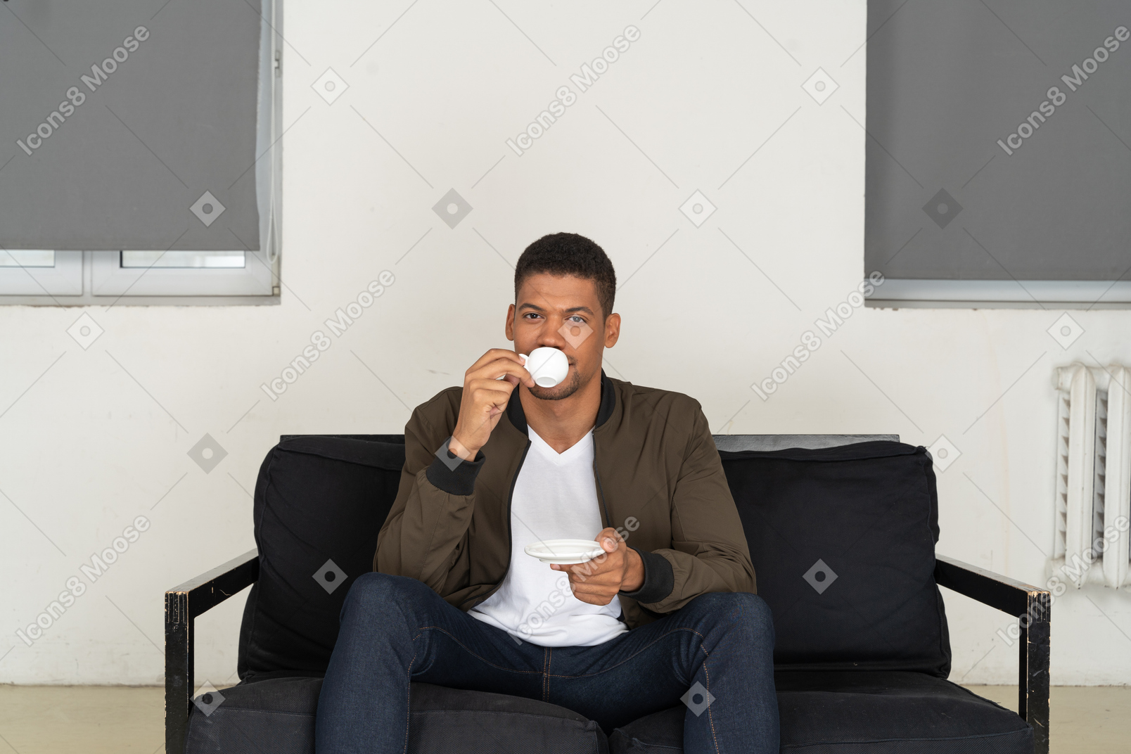 コーヒーを飲みながらソファに座って夢見る若い男の正面図