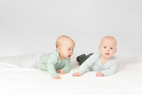 Curious babies twins lying on the stomach