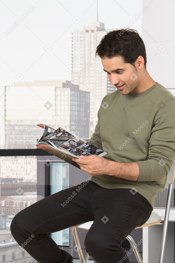 Young man sitting on a chair and reading a magazine