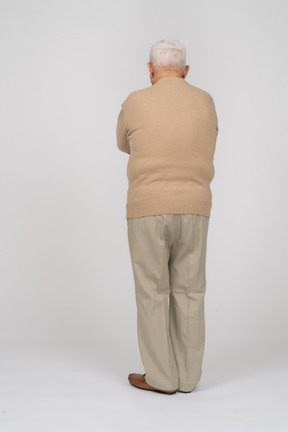 Вид сзади на старика в повседневной одежде, стоящего со скрещенными руками