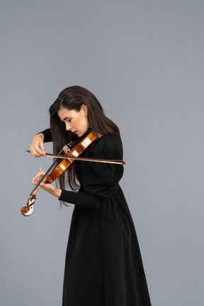 Close-up de uma jovem alegre de vestido preto tocando violino