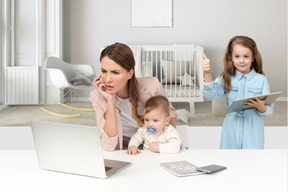 Mamá sosteniendo al bebé mientras trabaja en casa y su hija usando una tableta