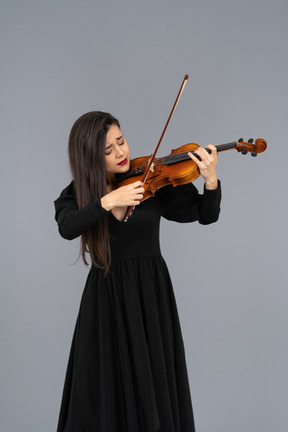 Close-up de uma jovem emocional de vestido preto tocando violino