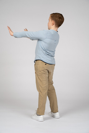 Side view of a boy standing with extended arms