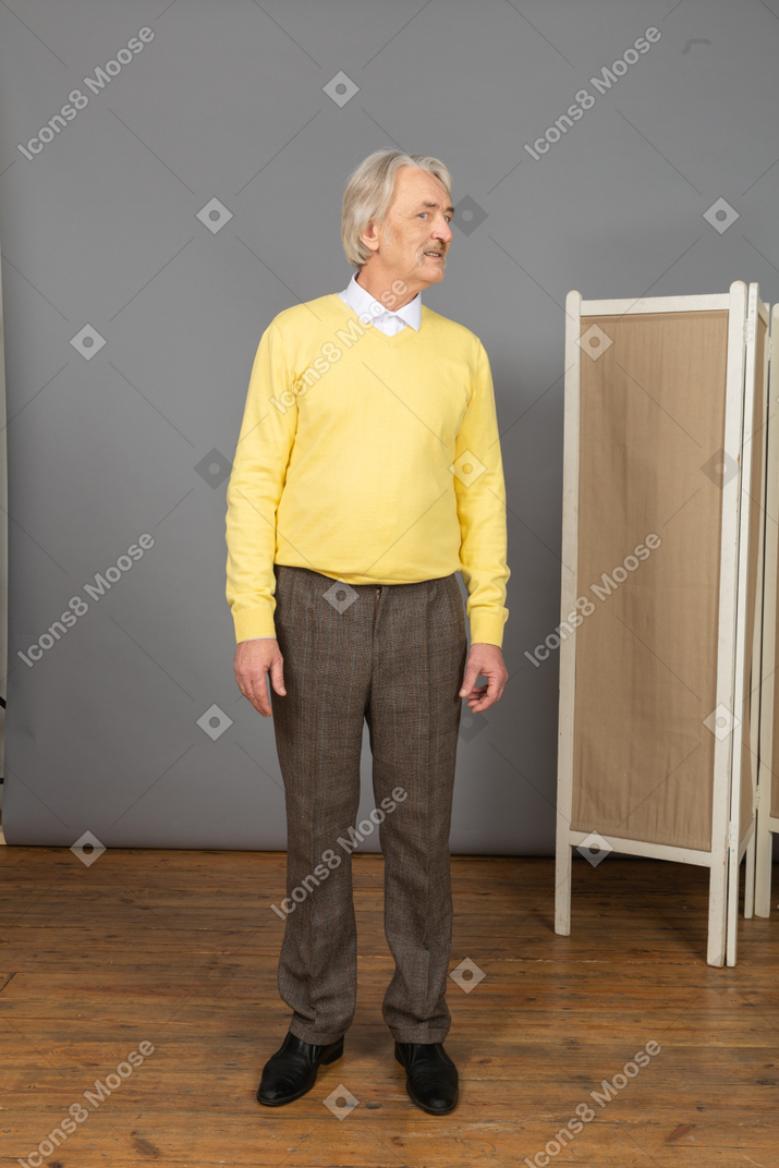 Front view of an old man in a yellow pullover turning head