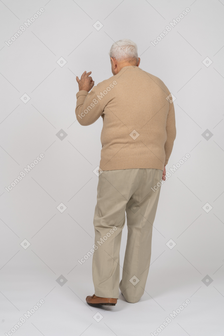 Okサインを示すカジュアルな服装の老人の背面図