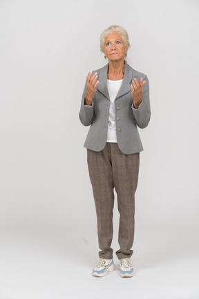 Front view of an old lady in suit standing with hands up