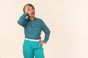 Femme noire avec une coupe de cheveux courte, tout en bleu, debout sur un fond pastel uni, à la recherche émotionnelle