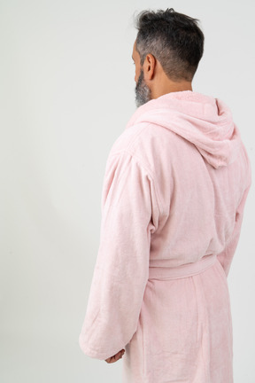 Человек в розовом халате стоит спиной