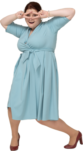 Front view of a woman in blue dress showing v signs