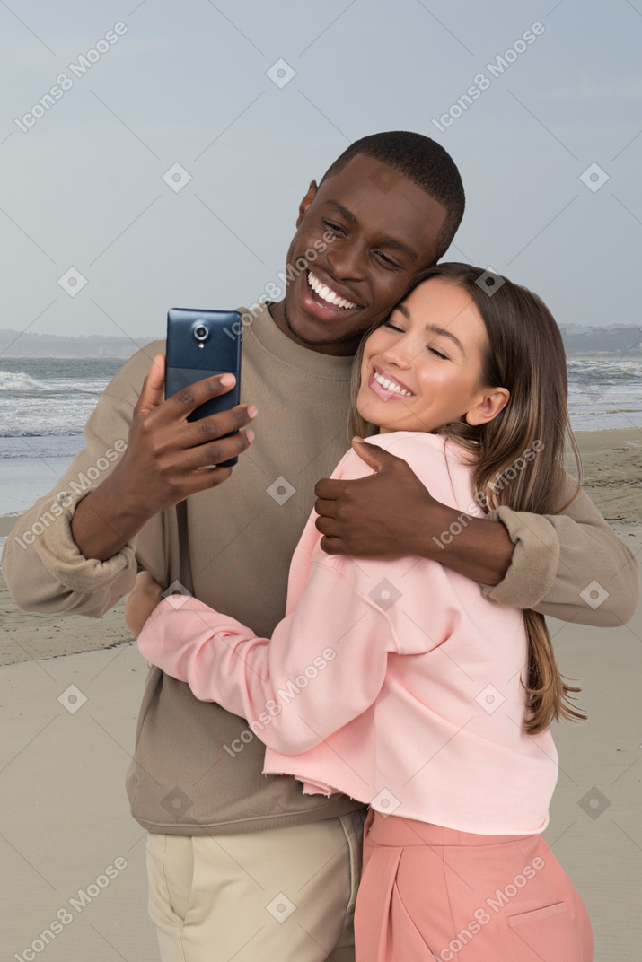 A man and woman taking a selfie on the beach