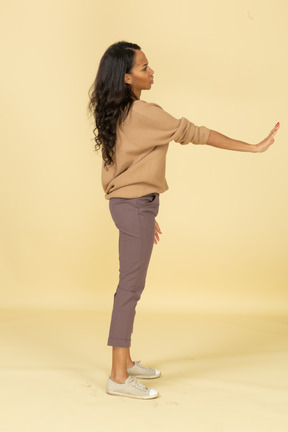 Side view of a dark-skinned young female outstretching hand