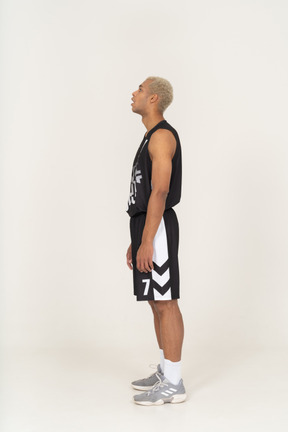 Vista laterale di un giovane giocatore di basket maschile ansimante