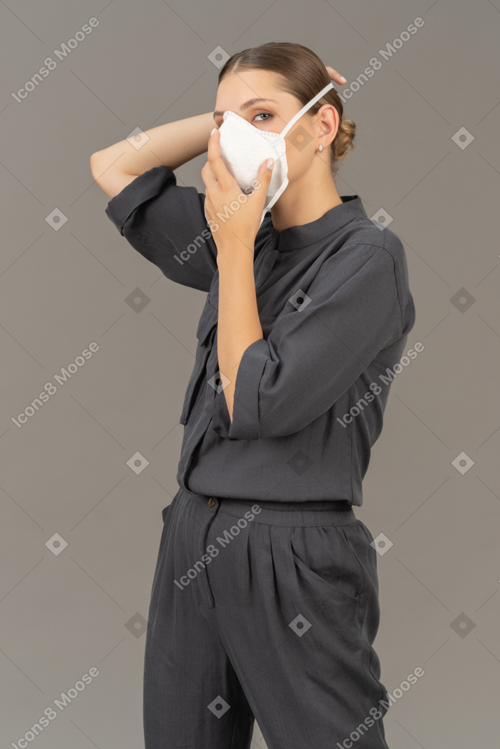 Mujer con overoles grises poniéndose un respirador