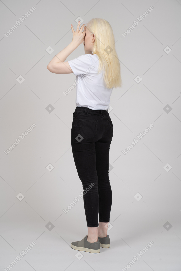 Vista posteriore di una donna dai capelli lunghi che si copre il viso