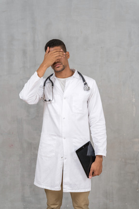 Overworked doctor covering his face