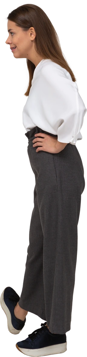 Side view of an arrogant young lady in office clothing putting hands on hips