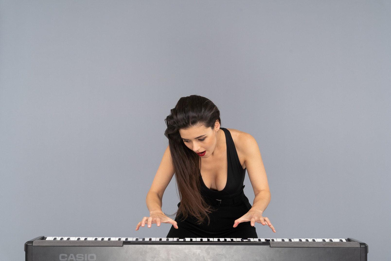 ピアノを弾く黒いドレスを着た若い女性の正面図 のフォト