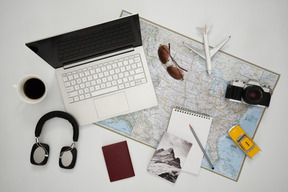 Laptop, headphones and other accessories arranged on a map