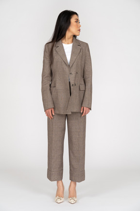 Front view of a young lady in brown business suit turning head while looking aside