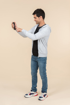 Young caucasian guy looking at smartphone