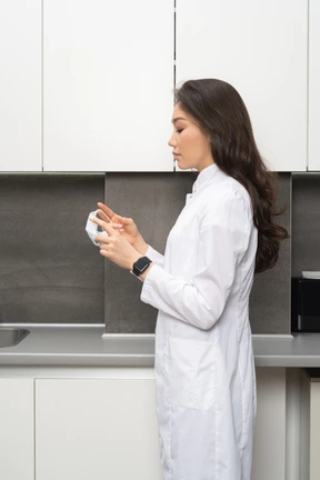Side view a female doctor holding a mask and looking down