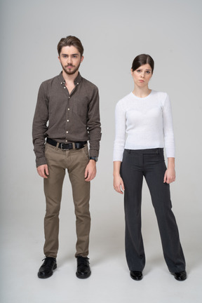 Front view of a displeased young couple in office clothing