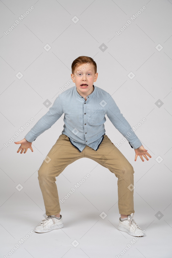 Front view of an angry boy squatting and looking at camera