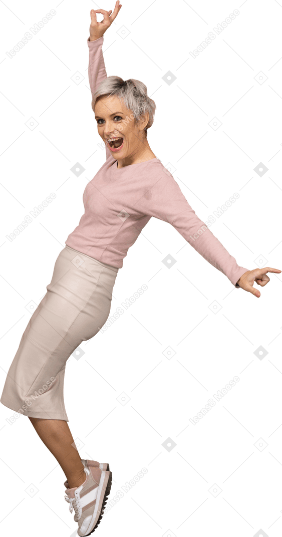 Vista lateral de una mujer feliz en ropa casual de pie sobre los dedos del pie