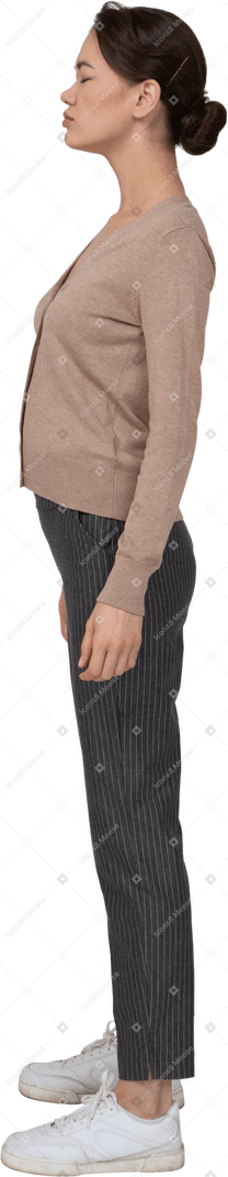 Vue latérale d'une jeune femme en pull et pantalon debout avec les yeux fermés