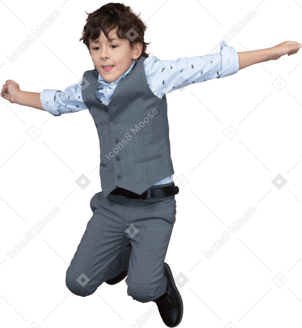 Vista frontal de un niño con traje saltando con los brazos extendidos