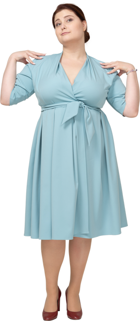 Vue de face d'une femme en robe bleue posant avec les mains sur les épaules